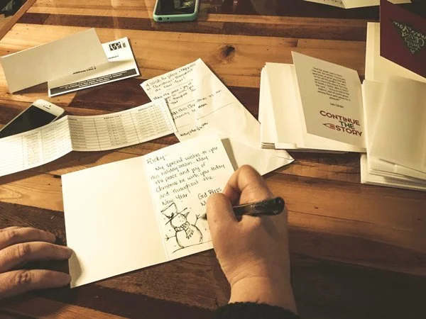 Christmas cards being handwritten and prepared for The Drop, a Continue the Story initiative sending holiday encouragement to people incarcerated in Ohio.